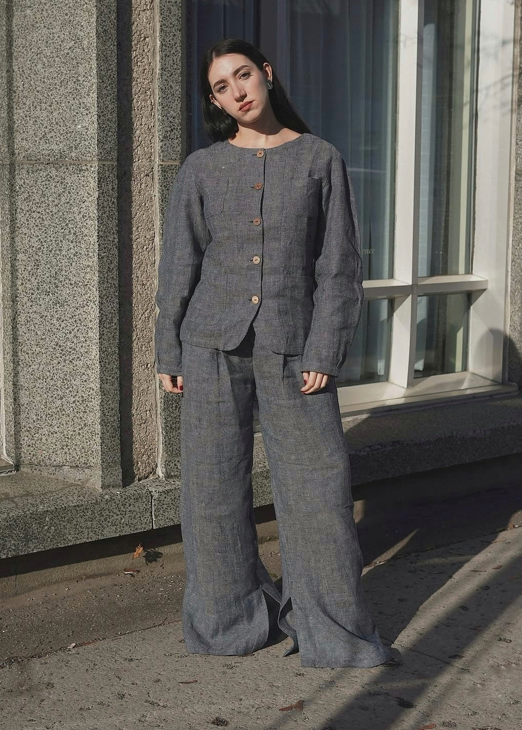 Woman wearing a gray suit standing outside a building.