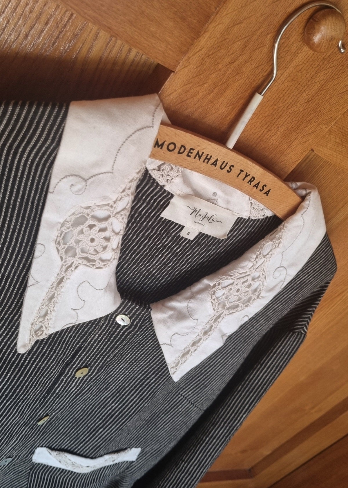 Black and white striped shirt with lace details on a hanger