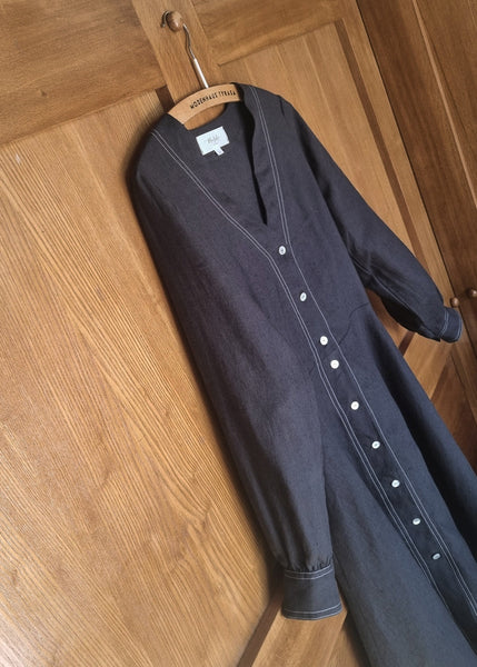 Black dress with white buttons on a wooden floor