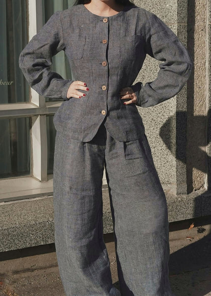 Person wearing a gray jumpsuit standing against a building.