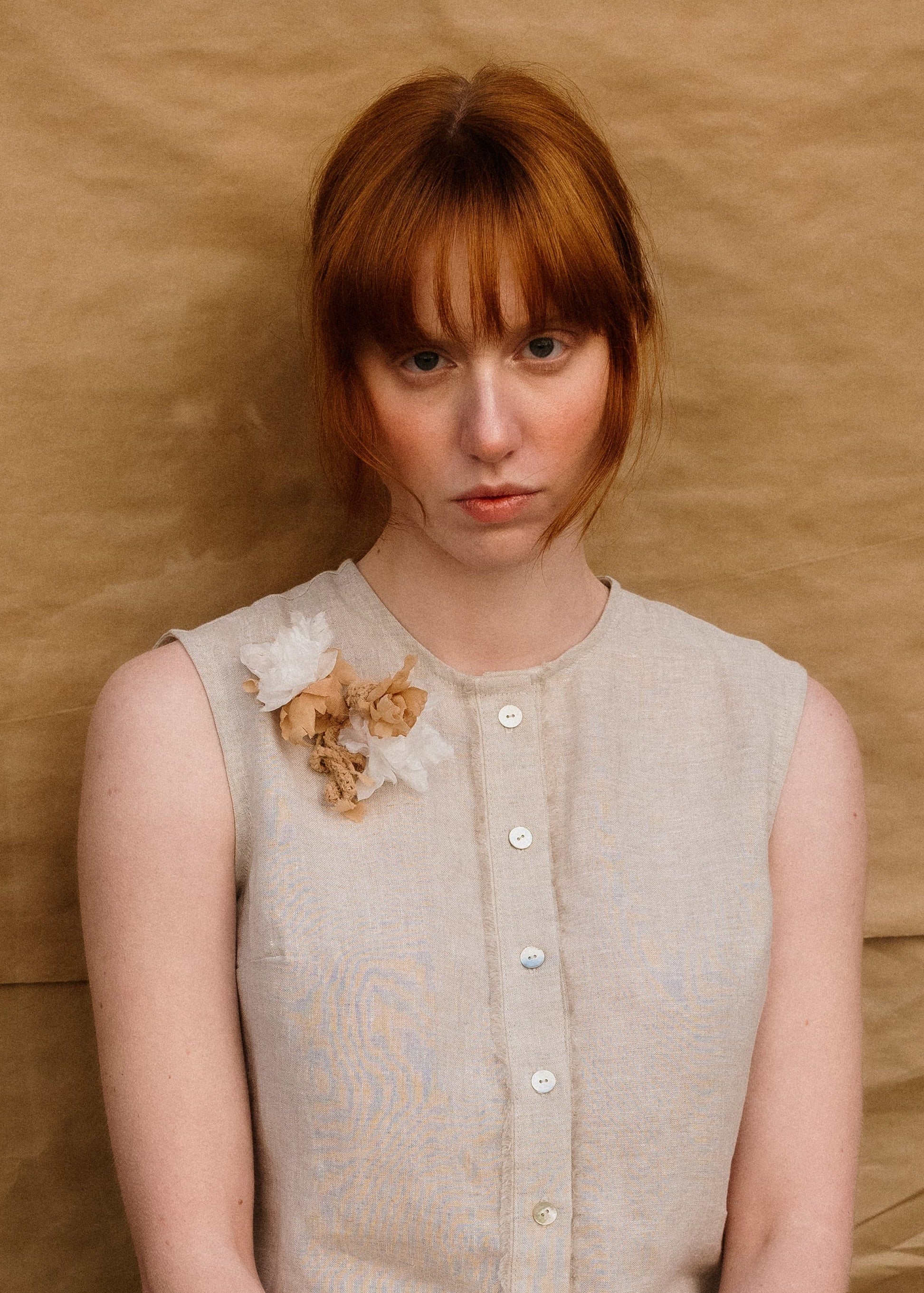 Woman in a light dress sitting against a plain background