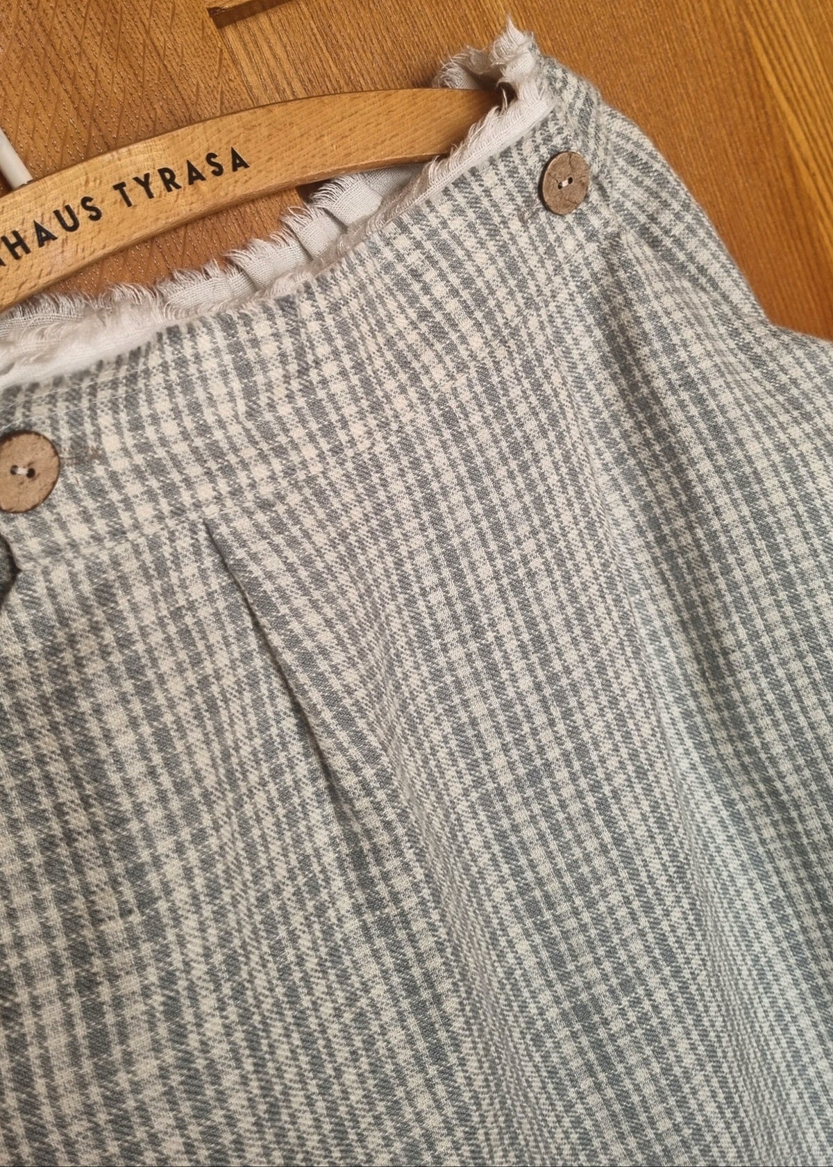 Plaid skirt with button details on a wooden hanger 