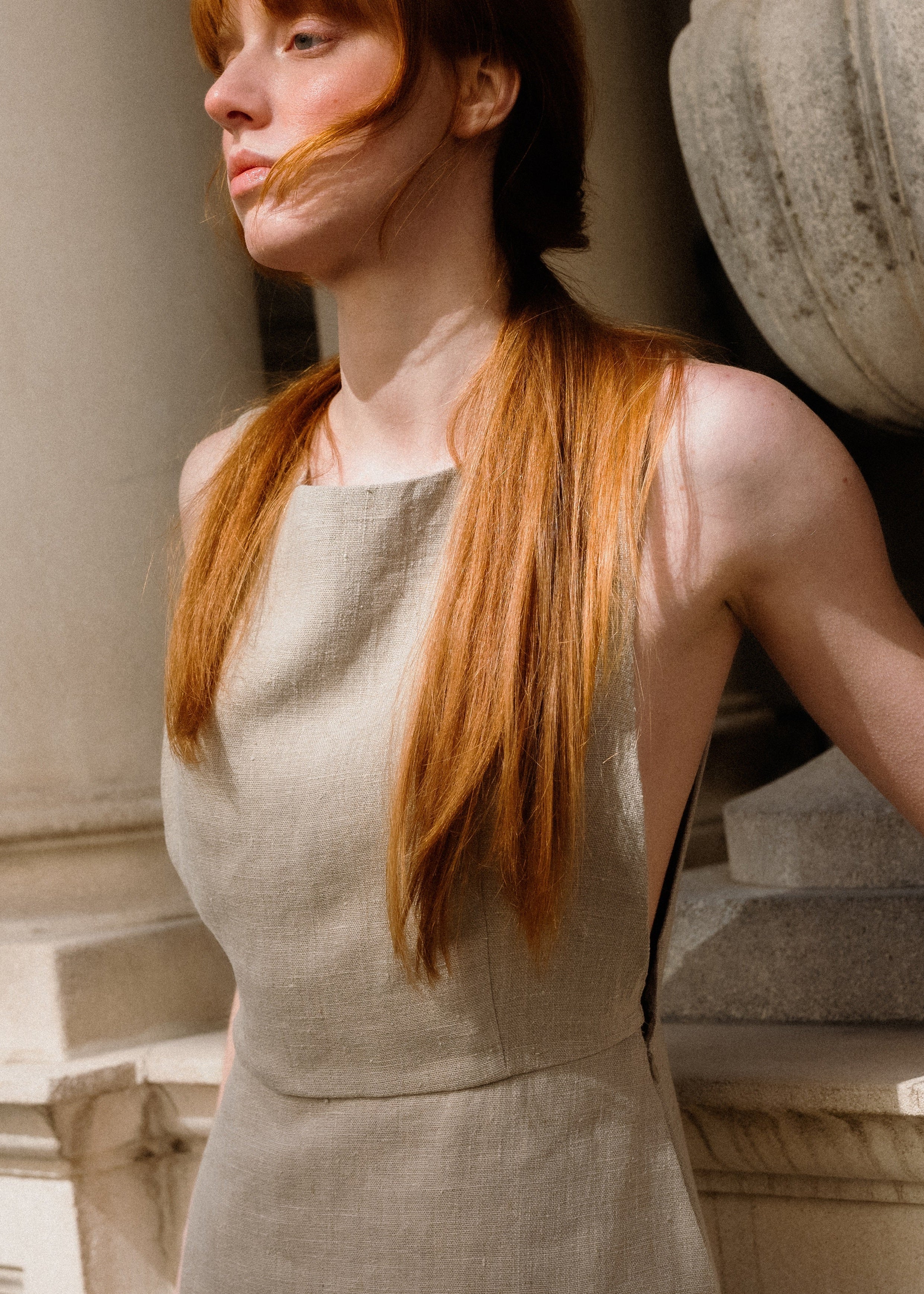 Woman in a light-colored dress standing against classical architecture