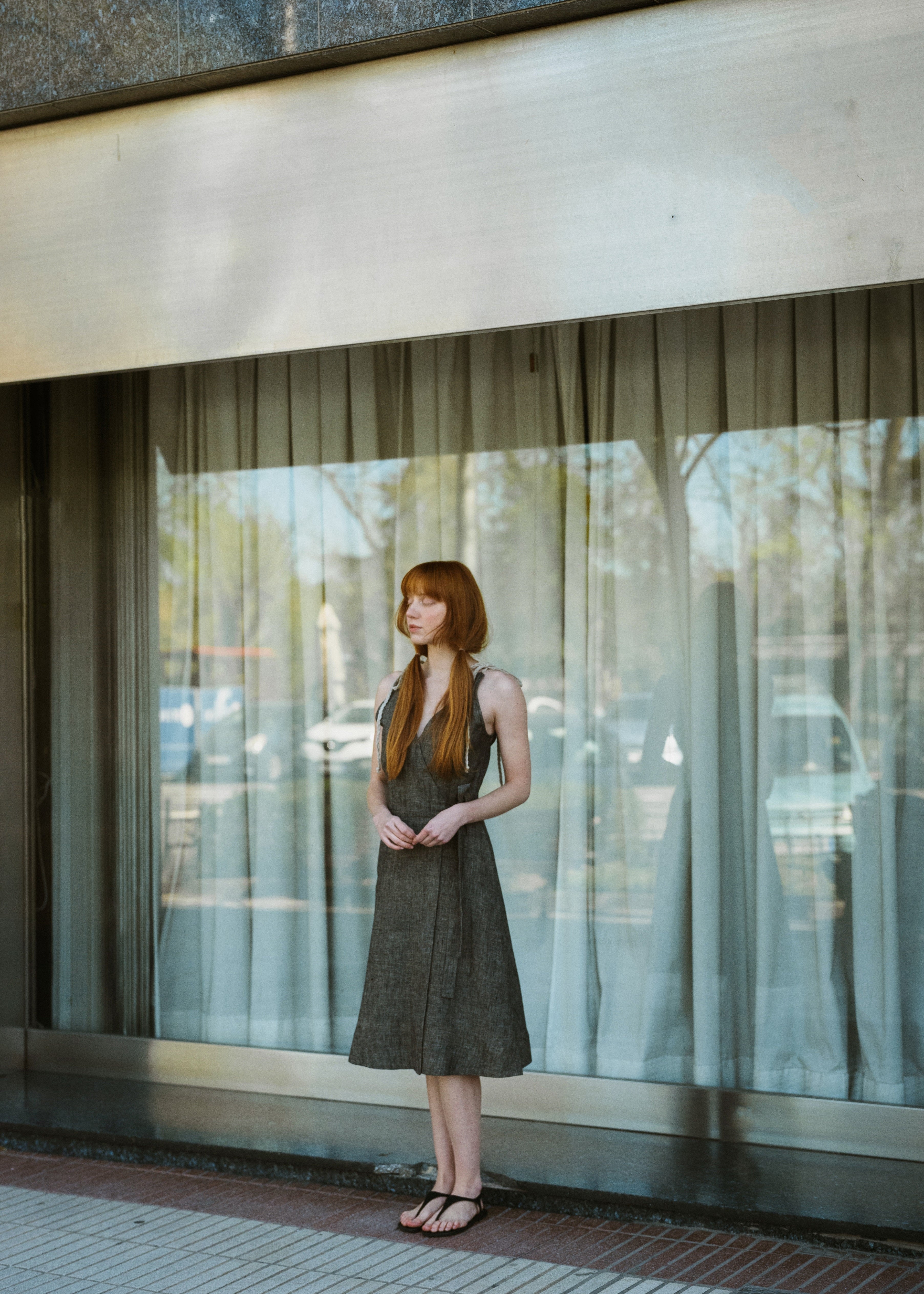 Woman standing in front of a glass wall with trees reflected