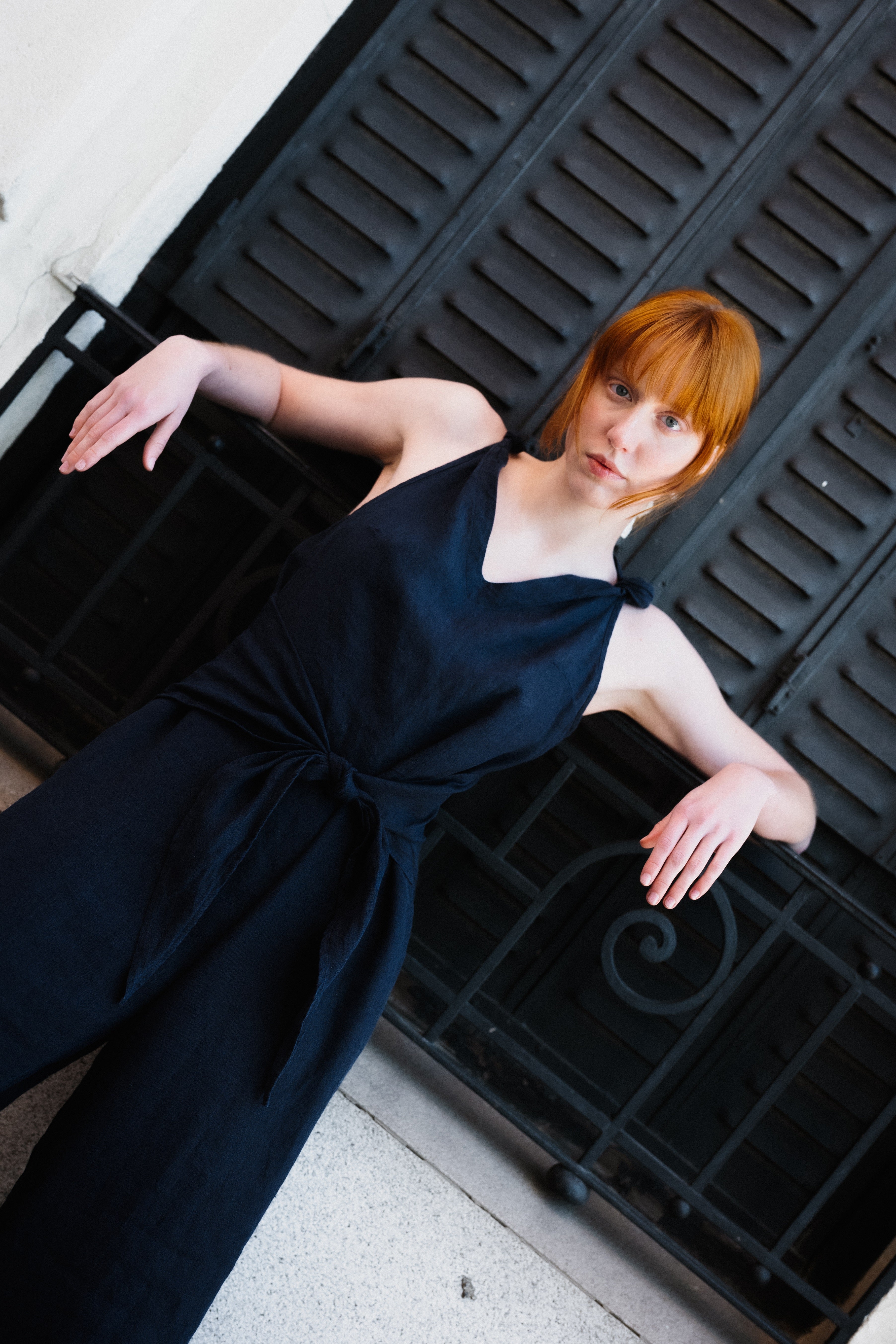 Woman in a black dress lying on a black metal grate.