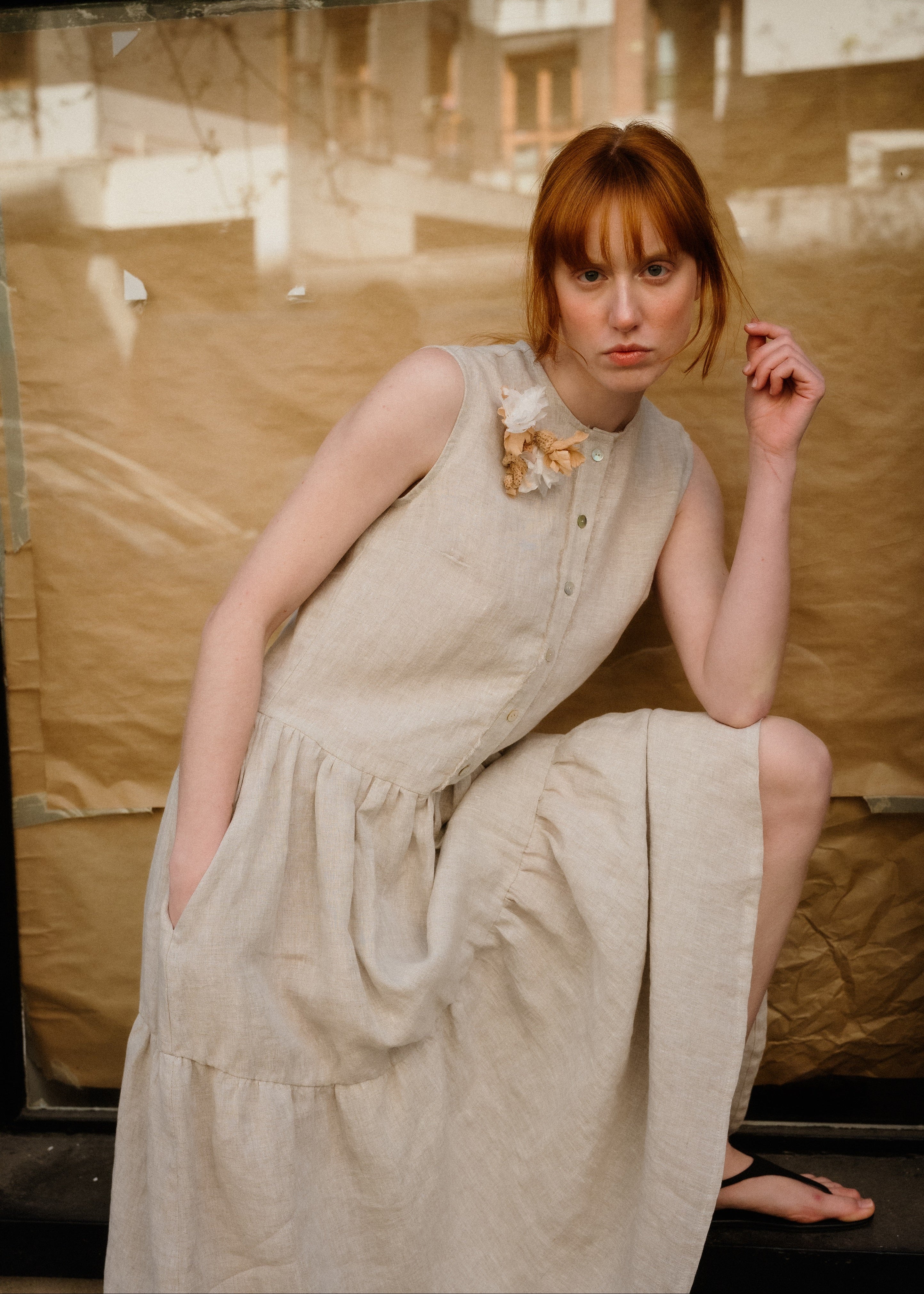Woman in a beige dress sitting on a couch with a blurred background