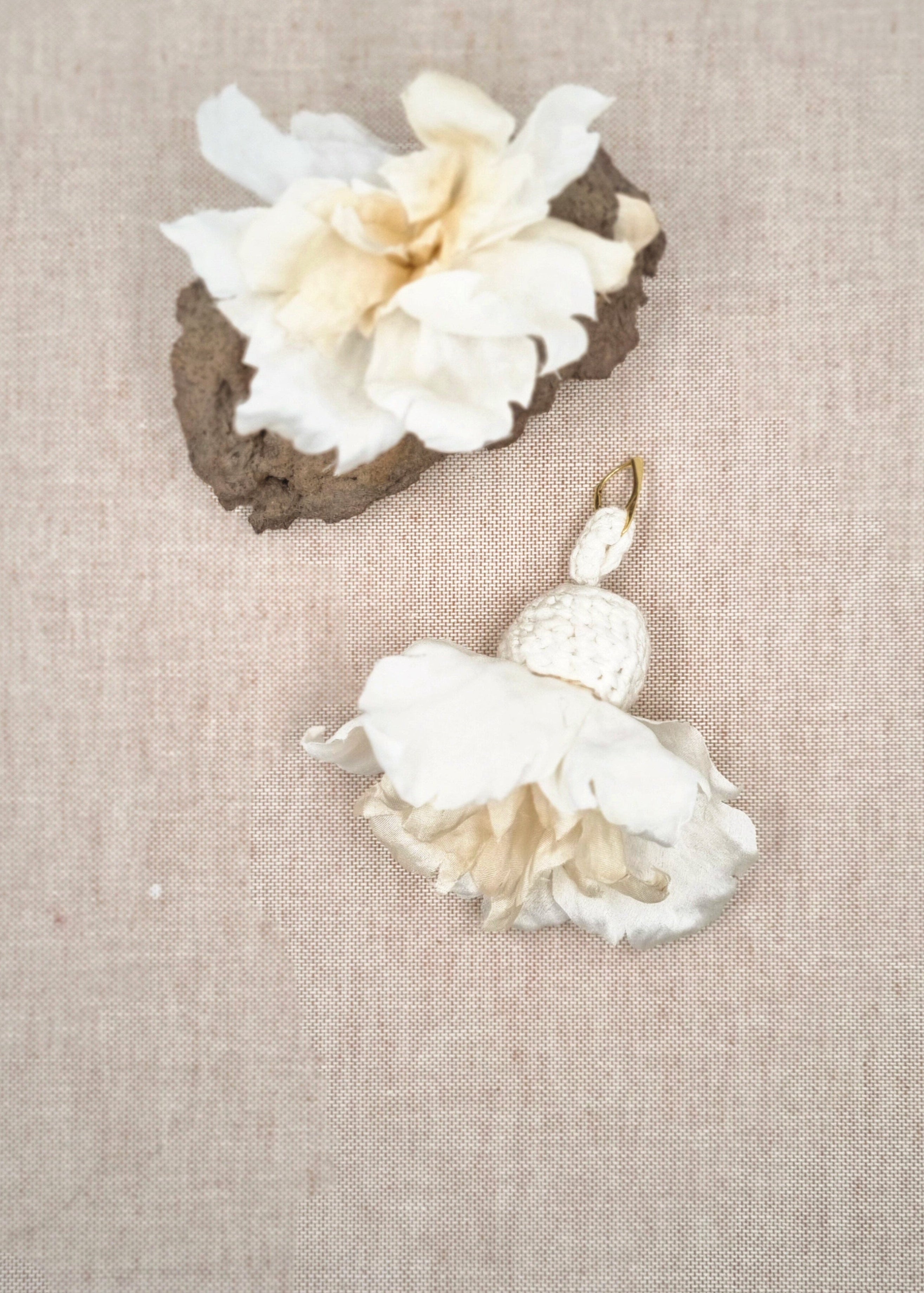 Pair of floral earrings on a textured beige fabric background