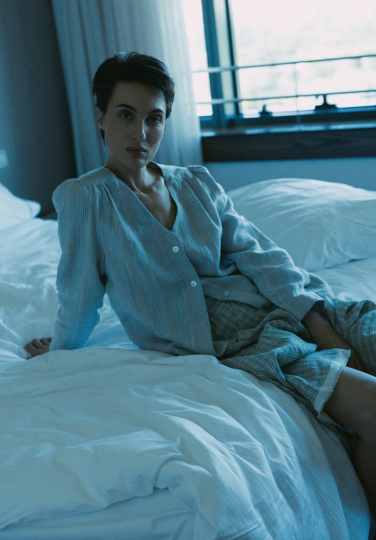 Woman sitting on a bed in a softly lit room