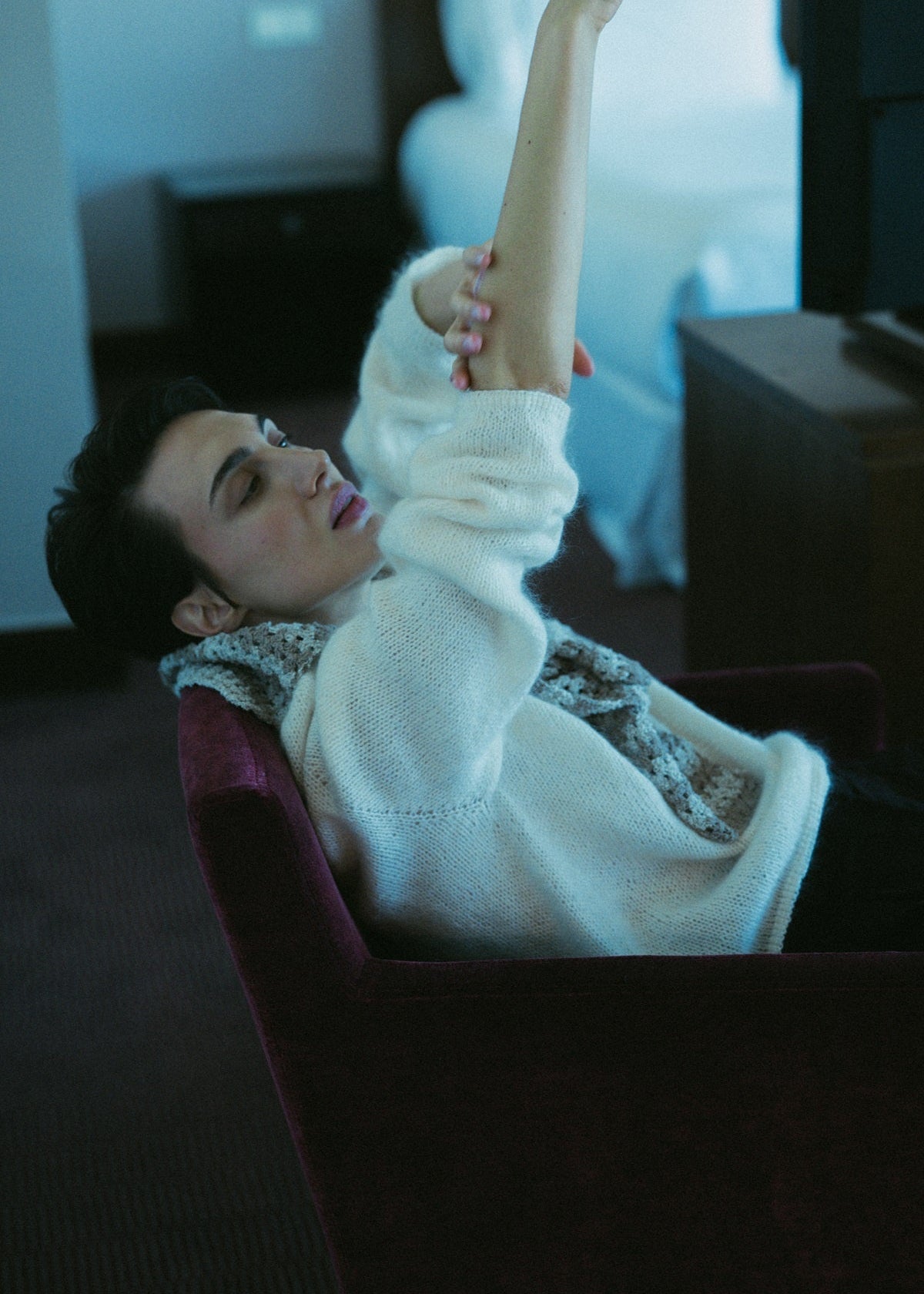 Person in a white sweater holding a leg in a dark room
