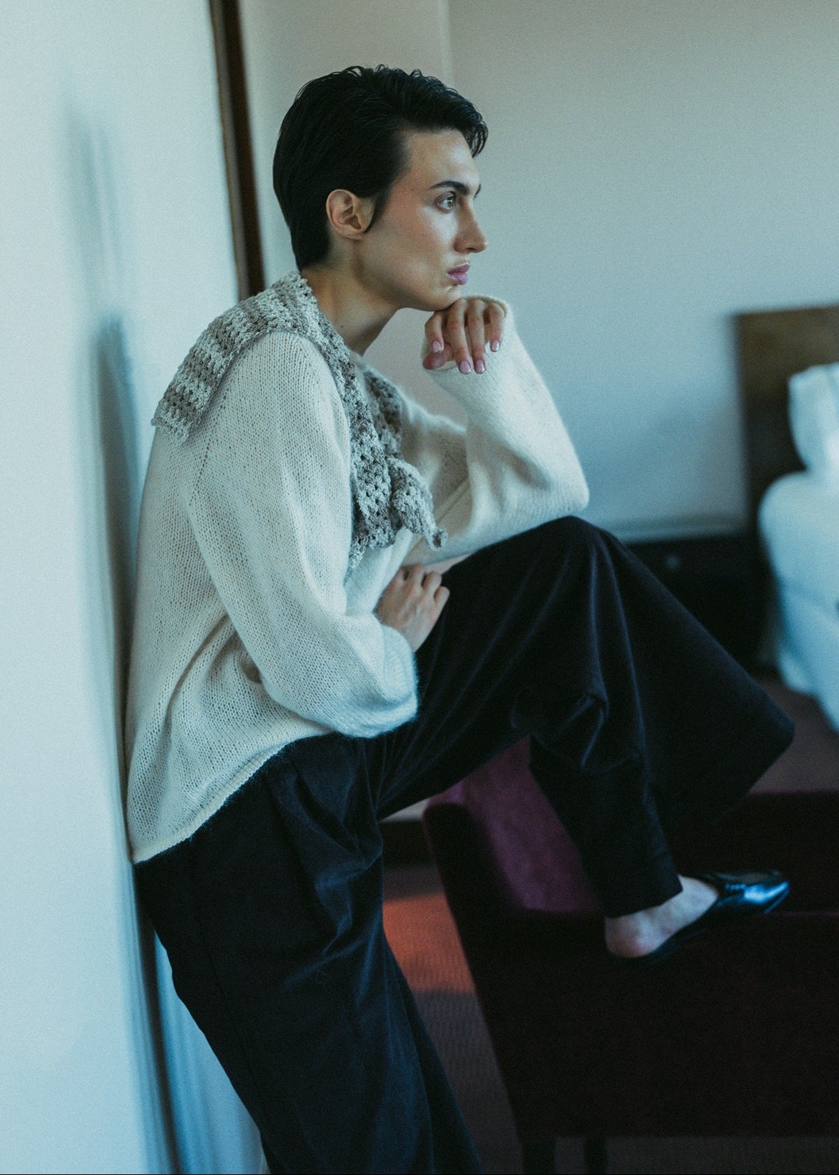 Person sitting on a bed in a room with a neutral color palette