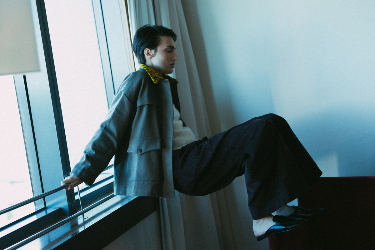 Person sitting by a window with a view of a cityscape