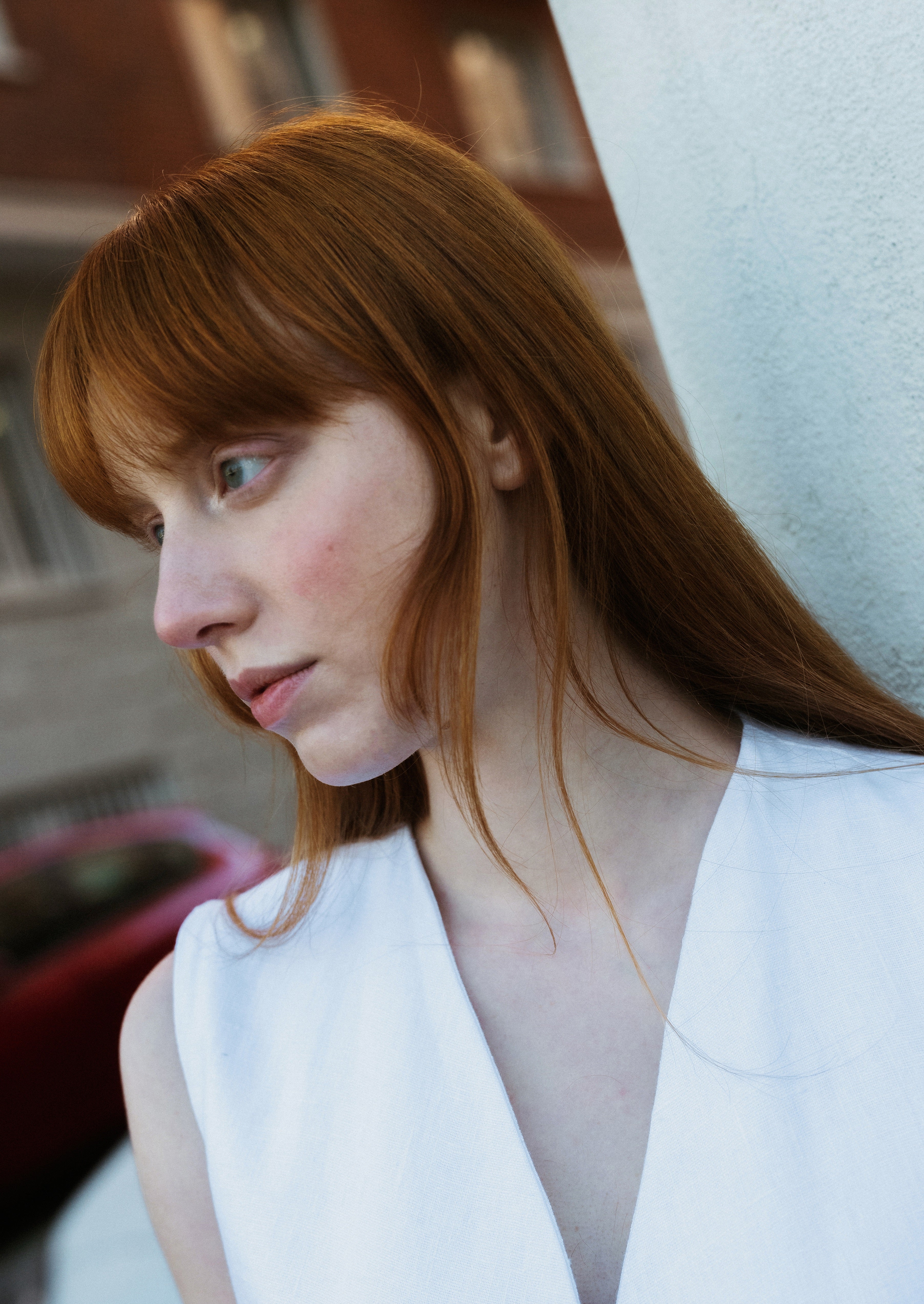 Woman with red hair wearing a white top in an indoor setting