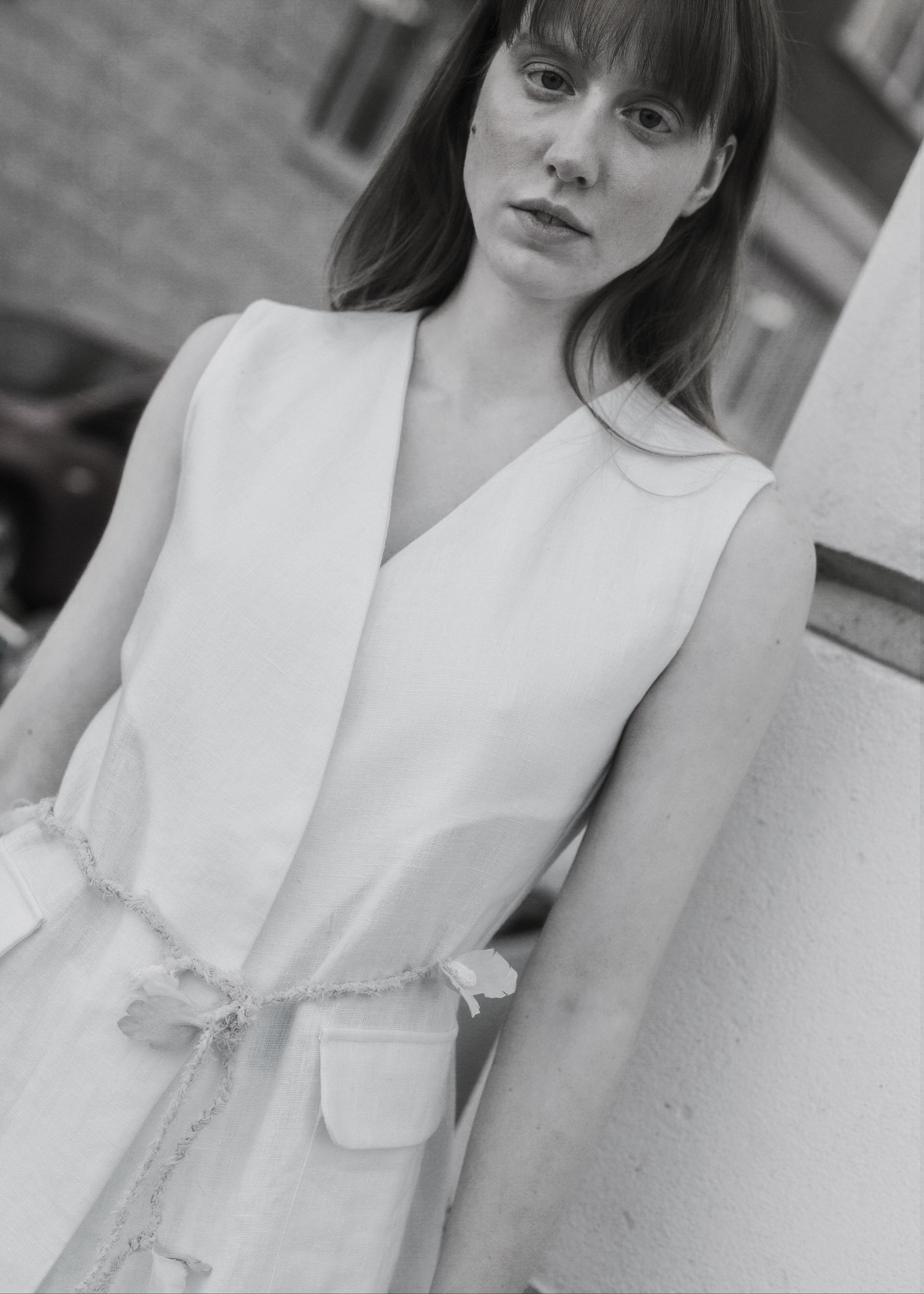Black and white photo of a person wearing a sleeveless outfit.